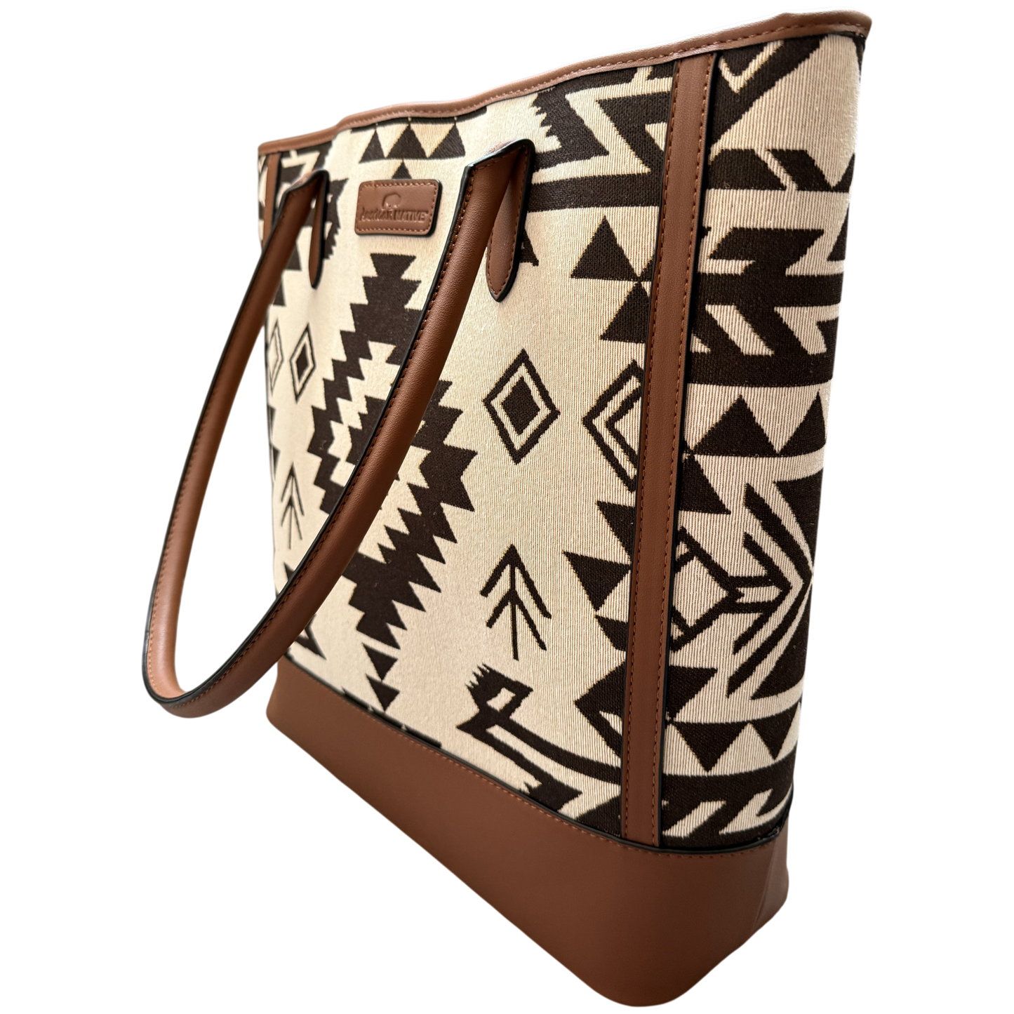 A tote bag with a Southwestern geometric pattern in beige and black, featuring brown faux-leather trim, handles, and base, shown on a plain white background.