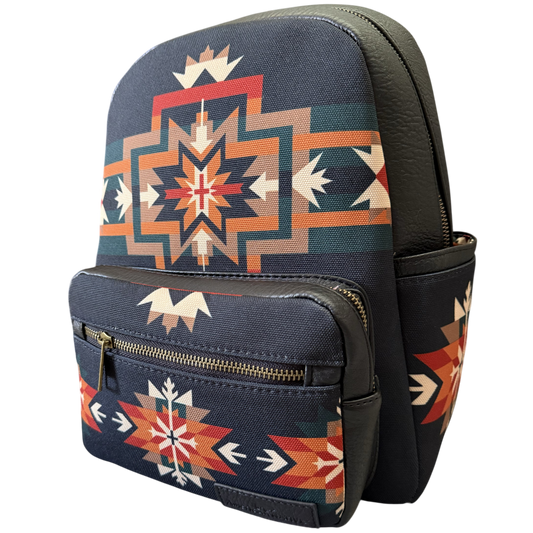 A small backpack with a navy blue base and a Southwestern geometric pattern in orange, red, beige, and teal, featuring dark brown faux-leather trim and a front zippered pocket.
