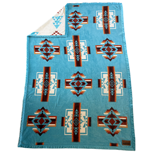 Blue patterned blanket with geometric designs on a white background
