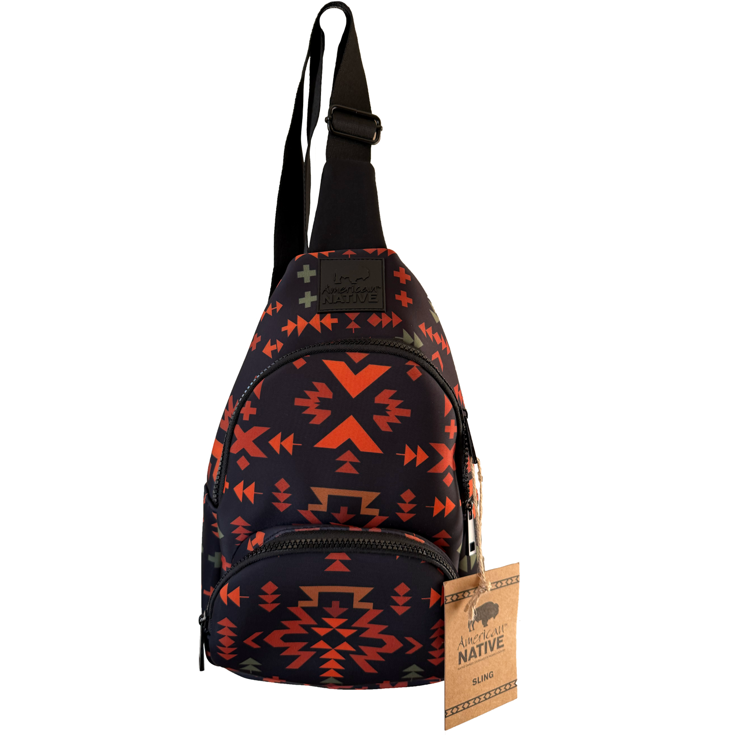 A small sling backpack with a black base and a Southwestern geometric pattern in orange, red, and brown. It features a black adjustable shoulder strap, a front zippered pocket, and a hanging paper tag that reads 'American Native'.