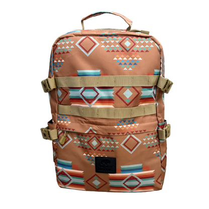 A backpack with a Southwestern geometric pattern in terracotta, beige, orange, and light blue, featuring tan webbing straps and a top handle, shown against a plain white background.