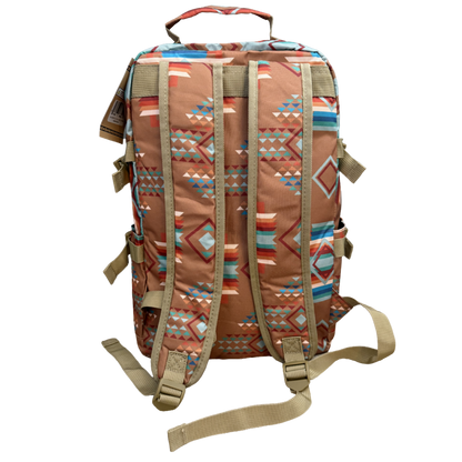 A backpack with a Southwestern geometric pattern in terracotta, beige, blue, and red, featuring tan webbing straps and a top carry handle, shown against a plain white background.
