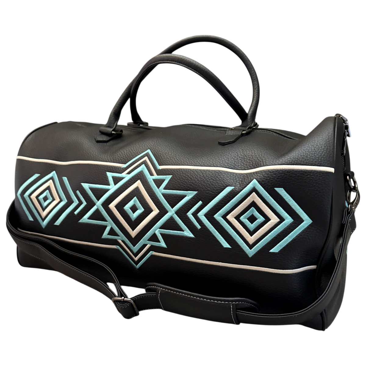 A black faux-leather duffel bag with a geometric Southwestern-style diamond pattern in turquoise, cream, and white, featuring dual top handles and a detachable shoulder strap.