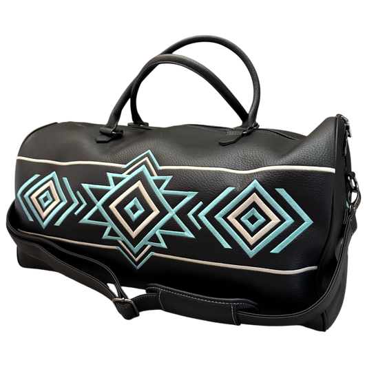 A black faux-leather duffel bag with a geometric Southwestern-style diamond pattern in turquoise, cream, and white, featuring dual top handles and a detachable shoulder strap.