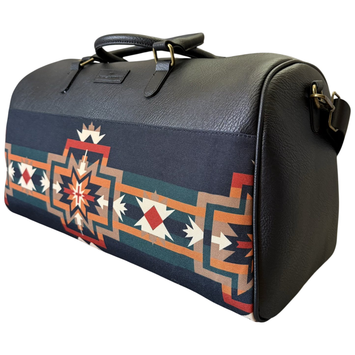 A black pebbled leather duffel bag featuring a Southwestern geometric patterned fabric panel on the front, with dark handles and gold-tone hardware, shown against a plain white background.