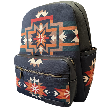 A small backpack with a navy blue base and a Southwestern geometric pattern in orange, red, beige, and teal, featuring dark brown faux-leather trim and a front zippered pocket.