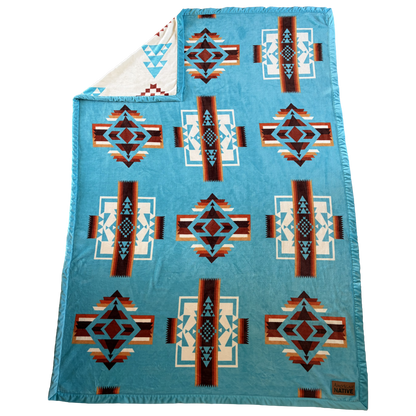 Blue patterned blanket with geometric designs on a white background