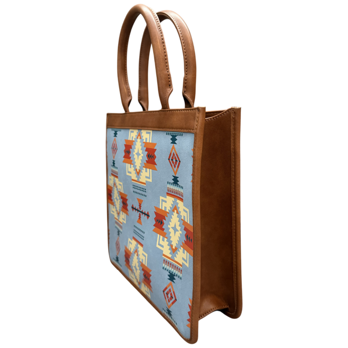 A structured tote bag with brown faux-leather handles and side panels, featuring a light blue front panel decorated with a Southwestern geometric pattern in orange, red, yellow, and dark blue.
