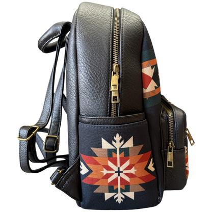 Black faux leather backpack with gold zippers and a Southwestern geometric pattern on the front pocket, shown against a plain white background.