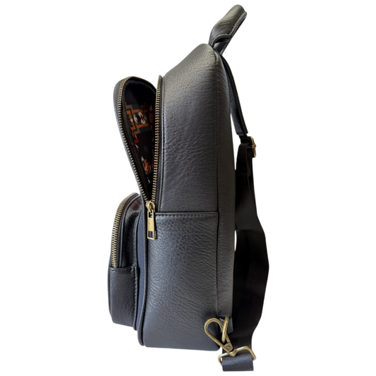 A dark gray pebbled leather crossbody bag shown from a side profile view, with its top zipper open to reveal a patterned lining, set against a plain white background.