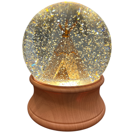 Snow globe with tee pee inside on wooden base on a white background