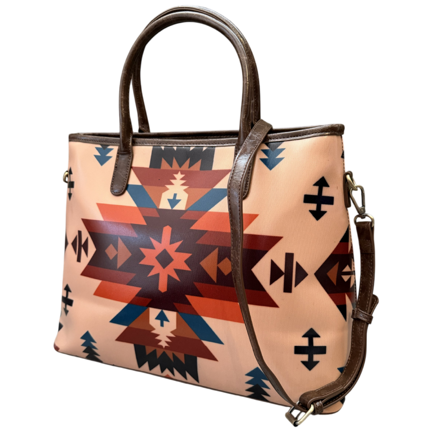 A structured tote bag featuring a Southwestern geometric pattern in terracotta, navy, and black on a light peach-beige background, with dark brown leather handles and trim.