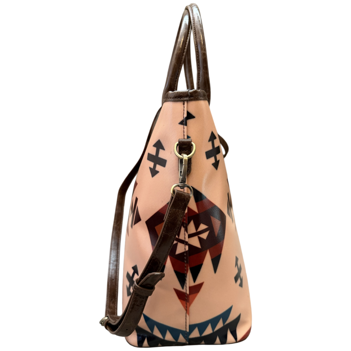 A structured leather shoulder bag with a light peach-beige body featuring a Southwestern geometric pattern in black, red, and blue, with dark brown leather handles and strap.