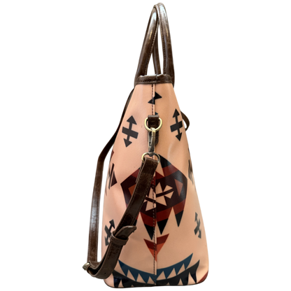 A structured leather shoulder bag with a light peach-beige body featuring a Southwestern geometric pattern in black, red, and blue, with dark brown leather handles and strap.