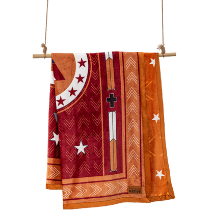 Orange reversible blanket with Native American design elements on a wooden stick
