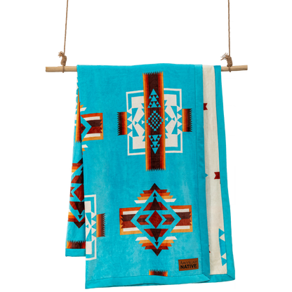 Turquoise blanket with geometric patterns hanging on a wooden rod 